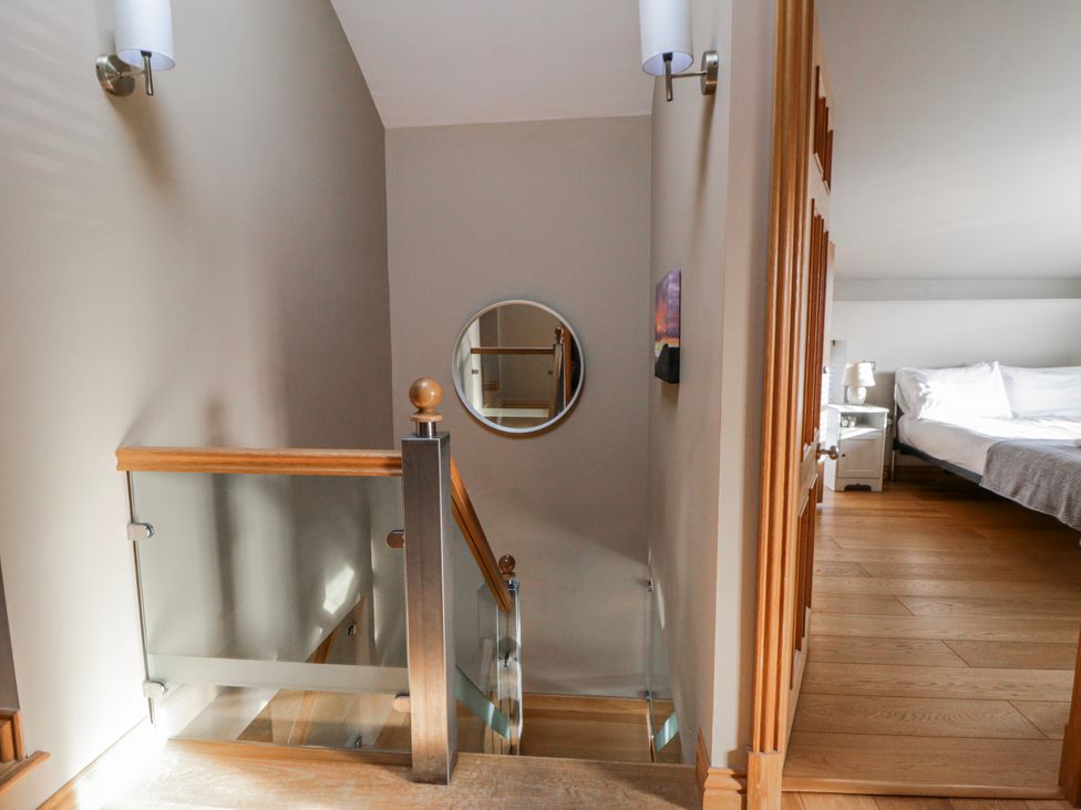 A staircase leading to a bedroom with a bed and lamp at Awelon Y Mor in Aberaeron