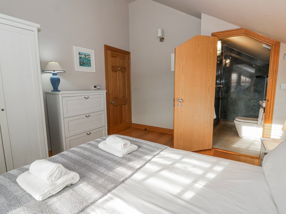 A bedroom with a bed and a bathroom door at Awelon Y Mor Aberaeron