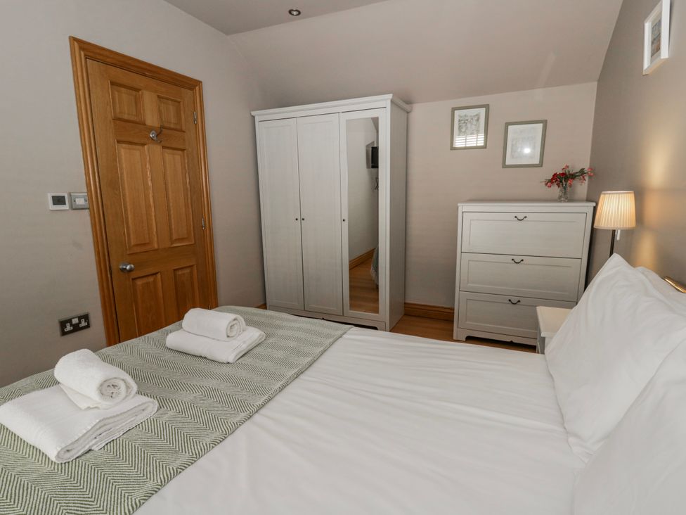 A bedroom with a bed and wardrobe at Awelon Y Mor in Aberaeron