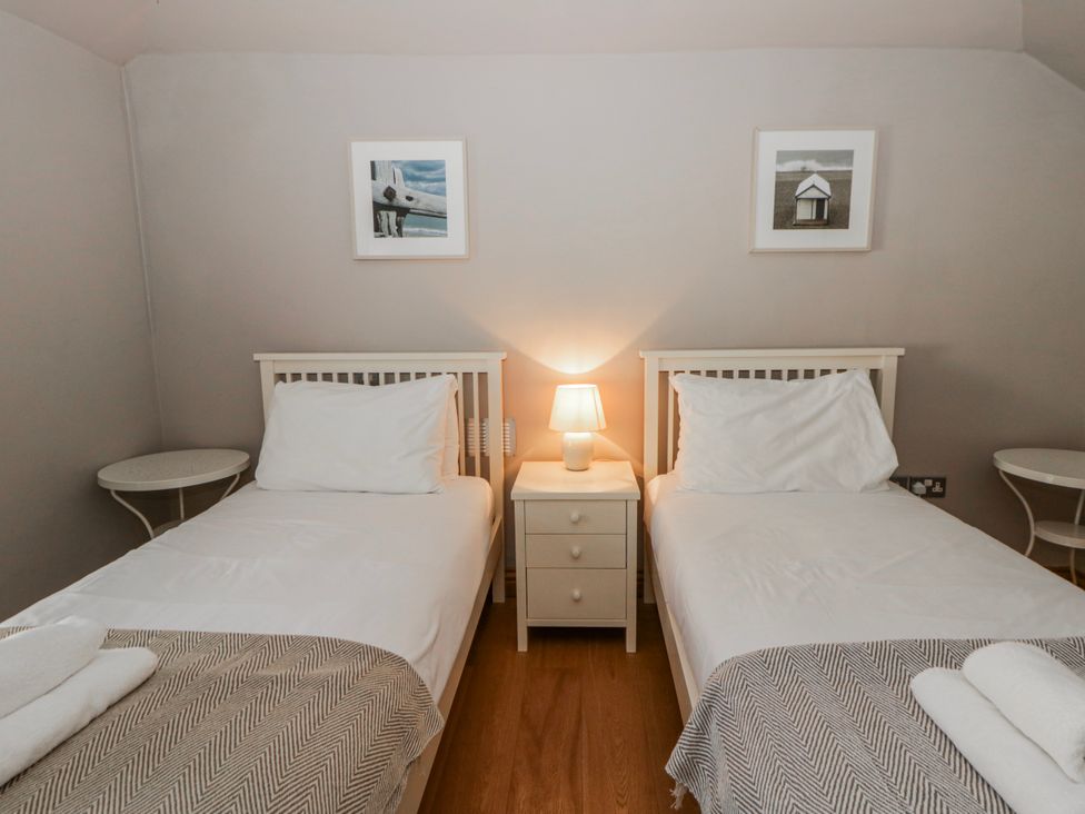 A bedroom with two single beds and a lamp at Awelon Y Mor in Aberaeron