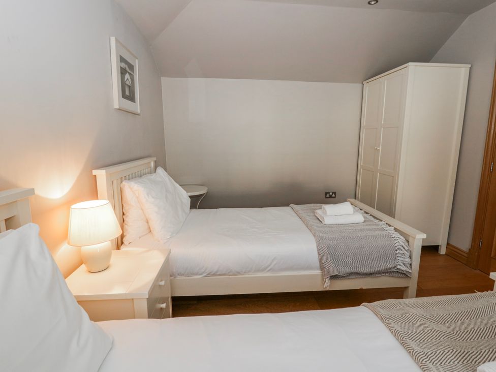 A bedroom with two beds and a wardrobe at Awelon Y Mor in Aberaeron