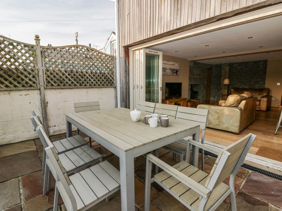 A patio with a dining set and sliding door at Awelon Y Mor in Aberaeron