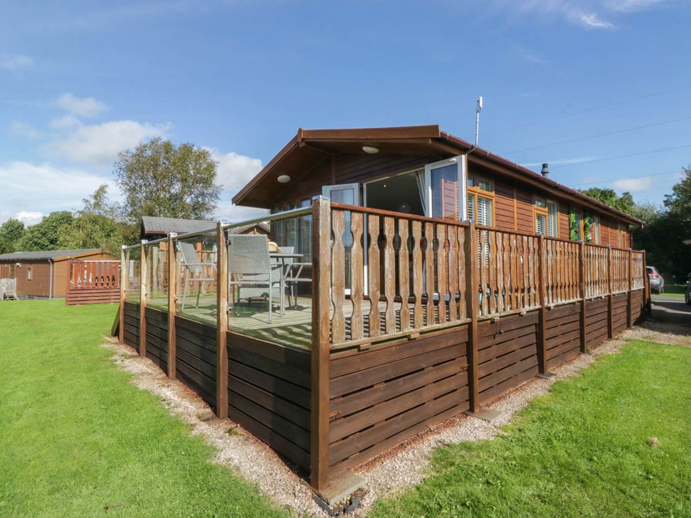 A lodge with decking and furniture in the outdoor area at South Lakeland Lodge. No. 46 Gressingham near Carnforth