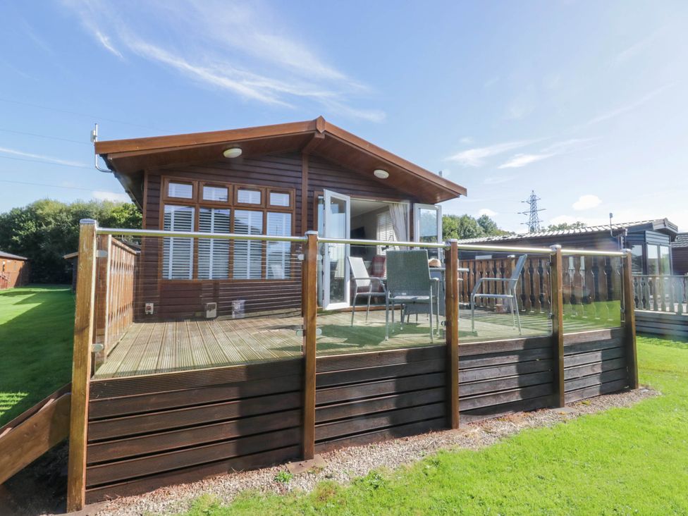 An outdoor lodge with decking and chairs at South Lakeland Lodge. No. 46 Gressingham near Carnforth