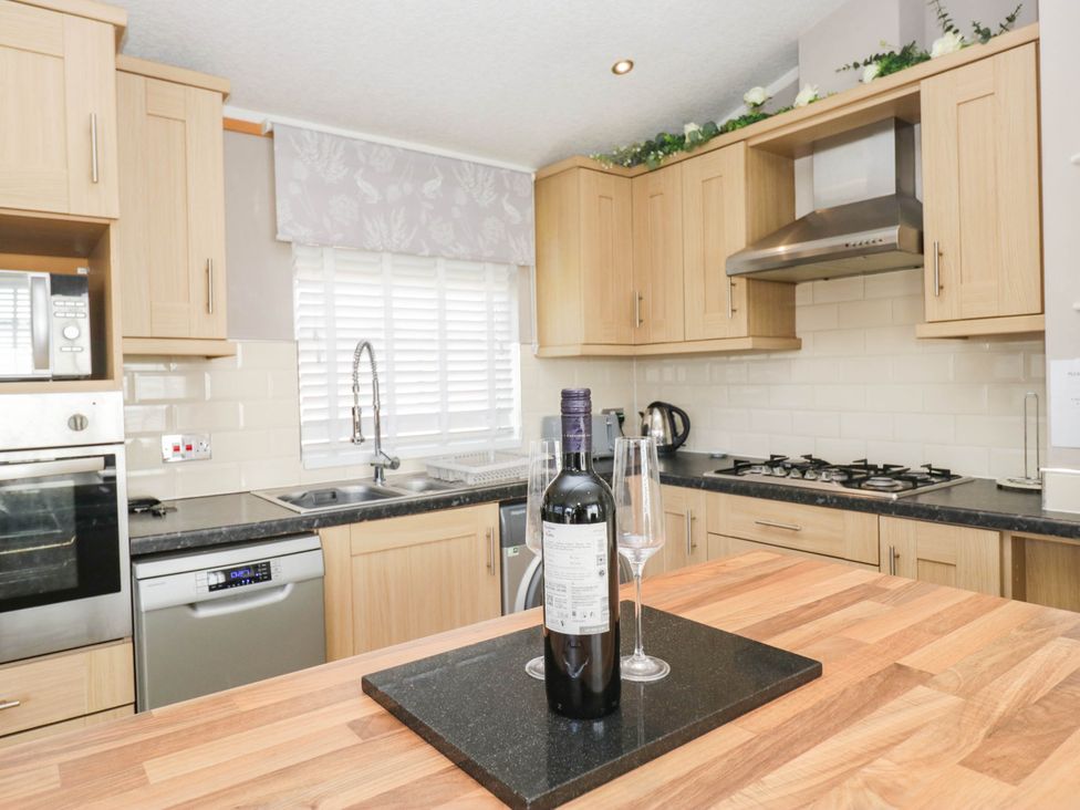 A kitchen with wooden cabinets and appliances at South Lakeland Lodge. No. 46 Gressingham near Carnforth