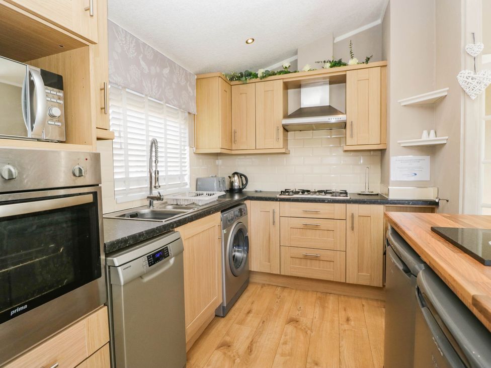 A kitchen with appliances and wooden cabinets at South Lakeland Lodge. No. 46 Gressingham near Carnforth