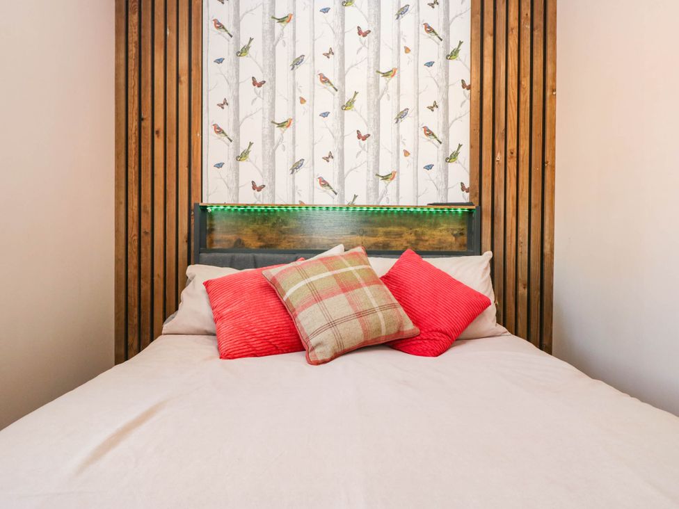 A bed with cushions and a patterned headboard at South Lakeland Lodge. No. 46 Gressingham near Carnforth