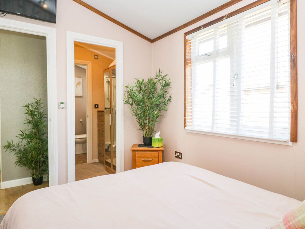 A bedroom with a bed and a bamboo plant at South Lakeland Lodge. No. 46 Gressingham near Carnforth