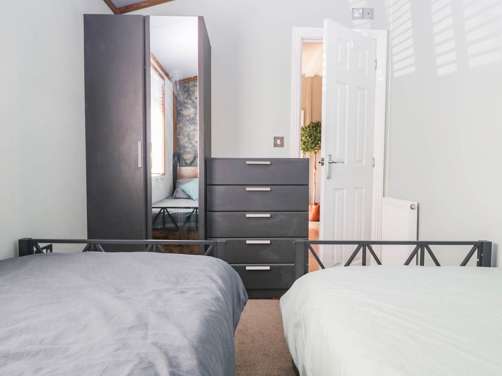 A bedroom with two beds and storage furniture at South Lakeland Lodge. No. 46 Gressingham near Carnforth
