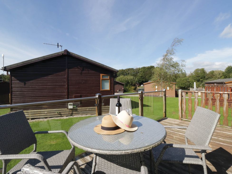 A table with chairs on a deck outside a cabin at South Lakeland Lodge No. 46 Gressingham near Carnforth