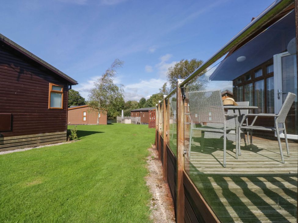 A garden with wooden cabins and a glass fence at South Lakeland Lodge. No. 46 Gressingham near Carnforth