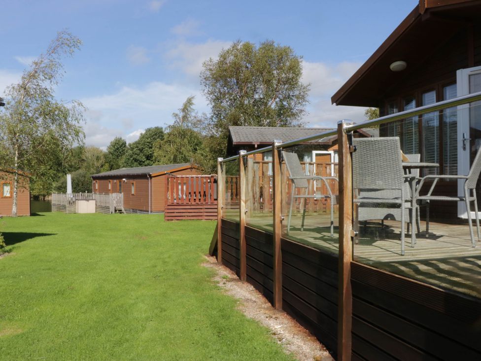 An outdoor area with a lodge and deck chairs at South lakeland Lodge. No. 46 Gressingham near Carnforth