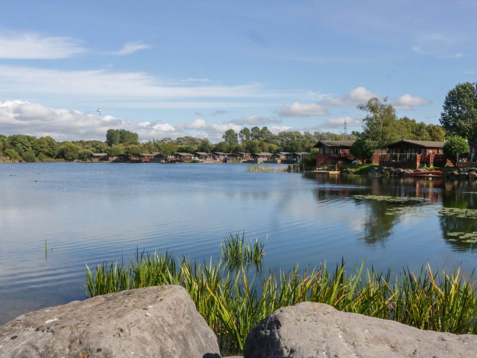 A lake with houses and trees surrounding it near South Lakeland Lodge. No. 46 Gressingham near Carnforth