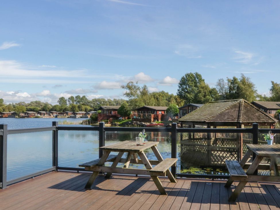 An outdoor area with tables and a view of a lake at South Lakeland Lodge. No. 46 Gressingham near Carnforth