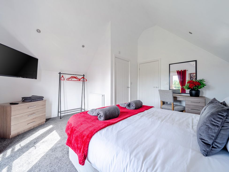 A bedroom with a bed, TV and dresser at Ruby Red Near Brigg