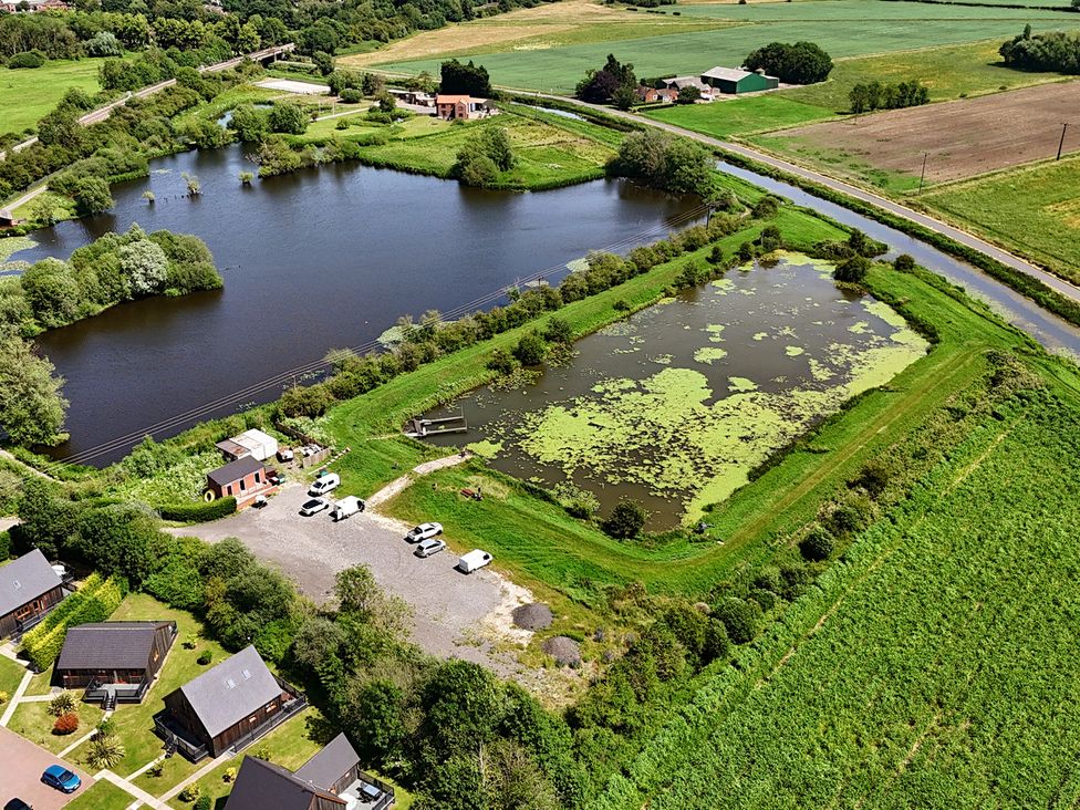 An outdoor area with a pond and surrounding greenery at Pumpkin Lodge near Brigg