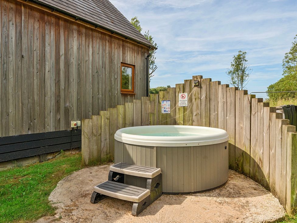 An outdoor area with a hot tub and wooden fence at Poker Lodge Near Brigg