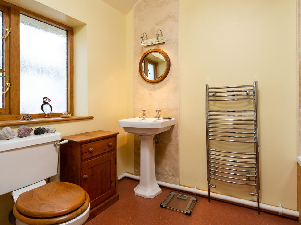 A bathroom with a sink, toilet, and mirror at Oakdene in Keswick