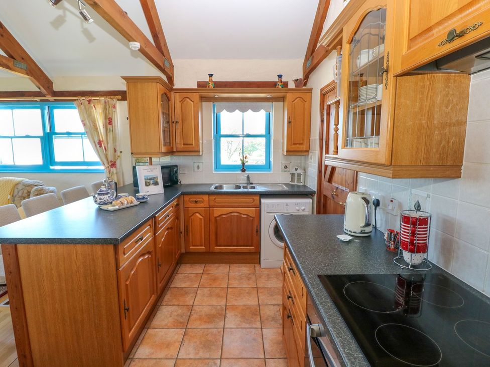 A kitchen with wooden cabinets and a washing machine at Casa Mia in Goodwick