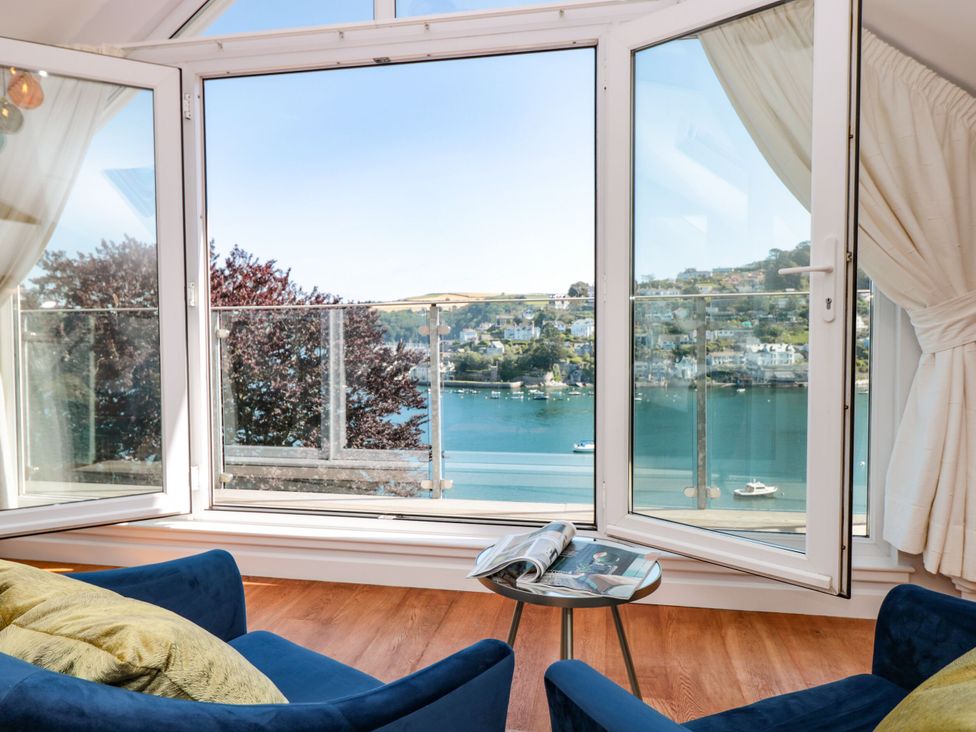 A living room with chairs and a table overlooking the water at Galvayne Dartmouth