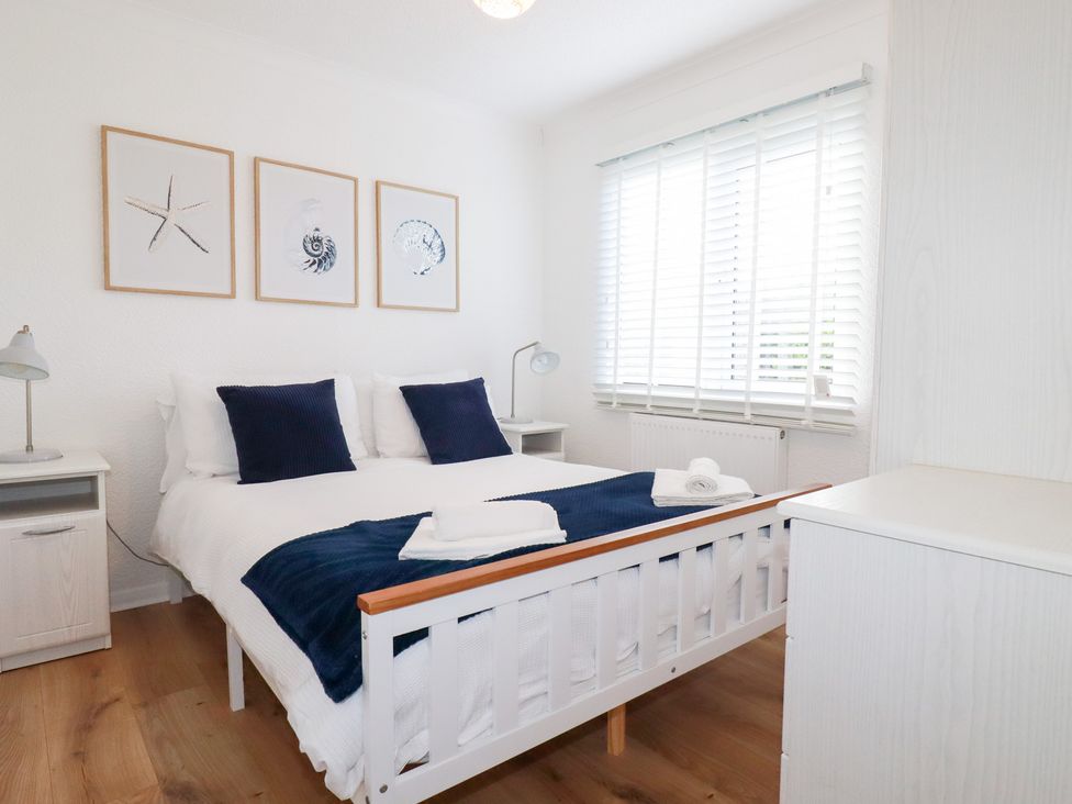 A bedroom with a bed, nightstands, and artwork at Ms Merryn 37 St. Cadocs