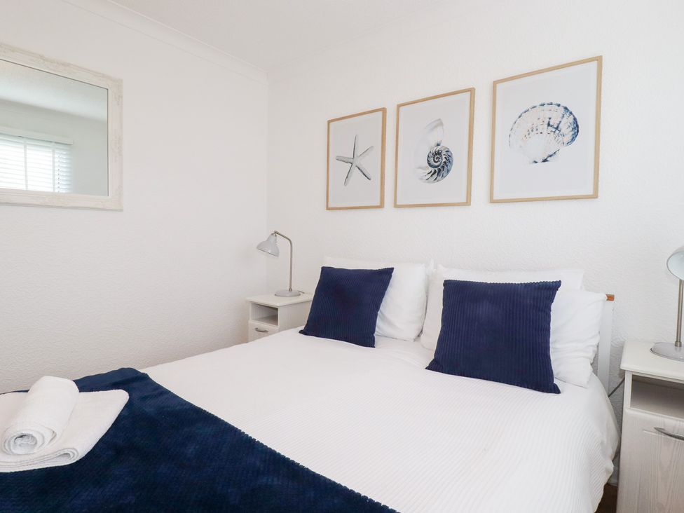 A bedroom with a bed, pillows, and framed pictures at Ms Merryn 37 St. Cadocs