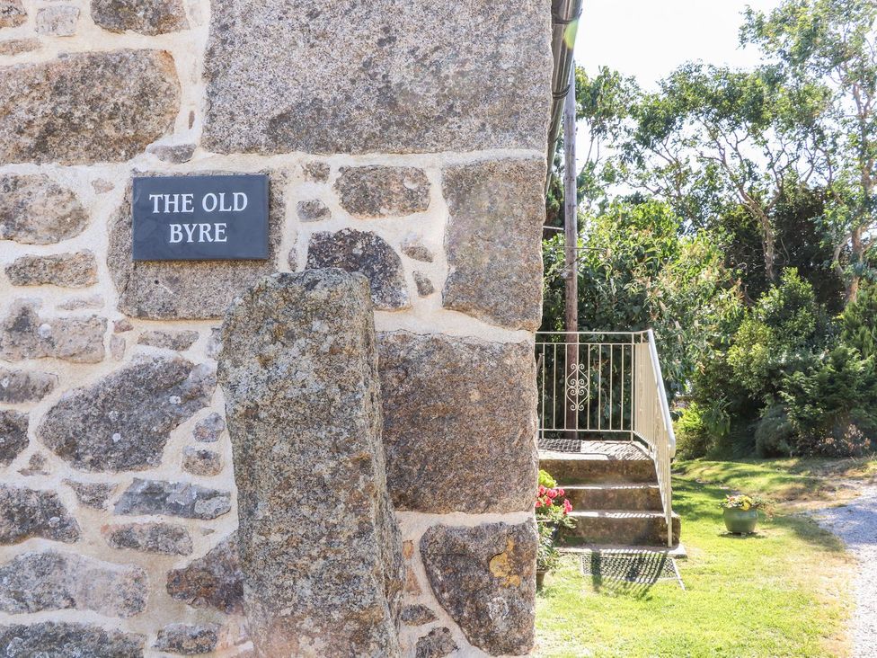 An exterior view of a stone wall and sign at The Old Byre in Falmouth
