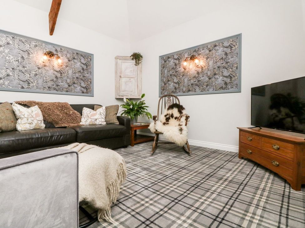 A living room with a sofa and television at The Old Byre in Falmouth