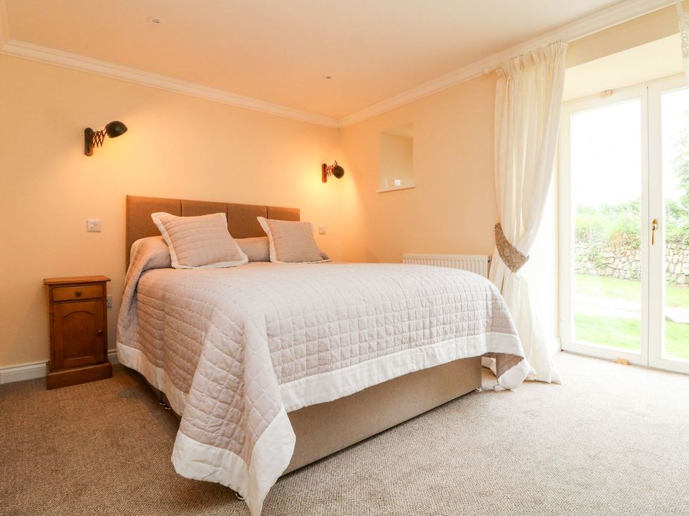 A bedroom with a bed and bedside table at The Old Byre in Falmouth