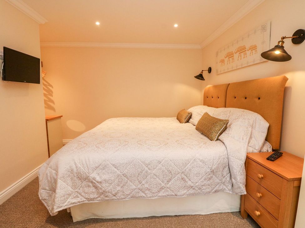 A bedroom with a bed and a television at The Old Byre in Falmouth
