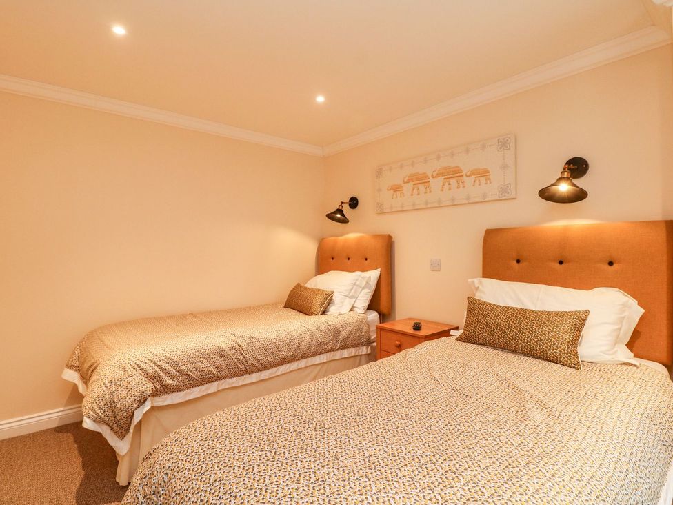 A bedroom with two beds and a nightstand at The Old Byre in Falmouth