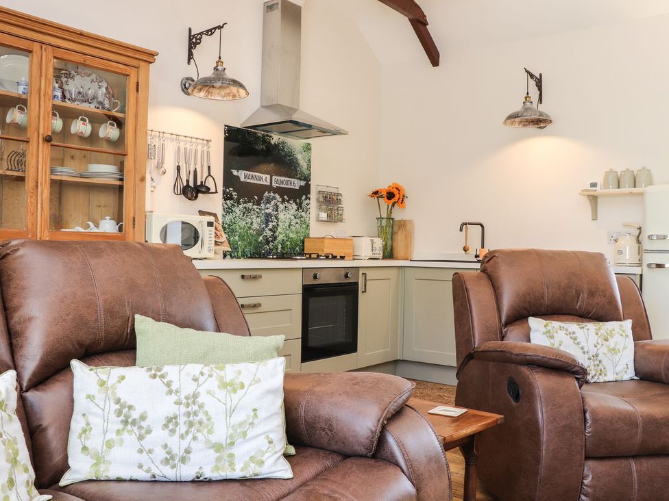 A living room with a sofa, kitchen cabinet, and stove at The Forge in Falmouth