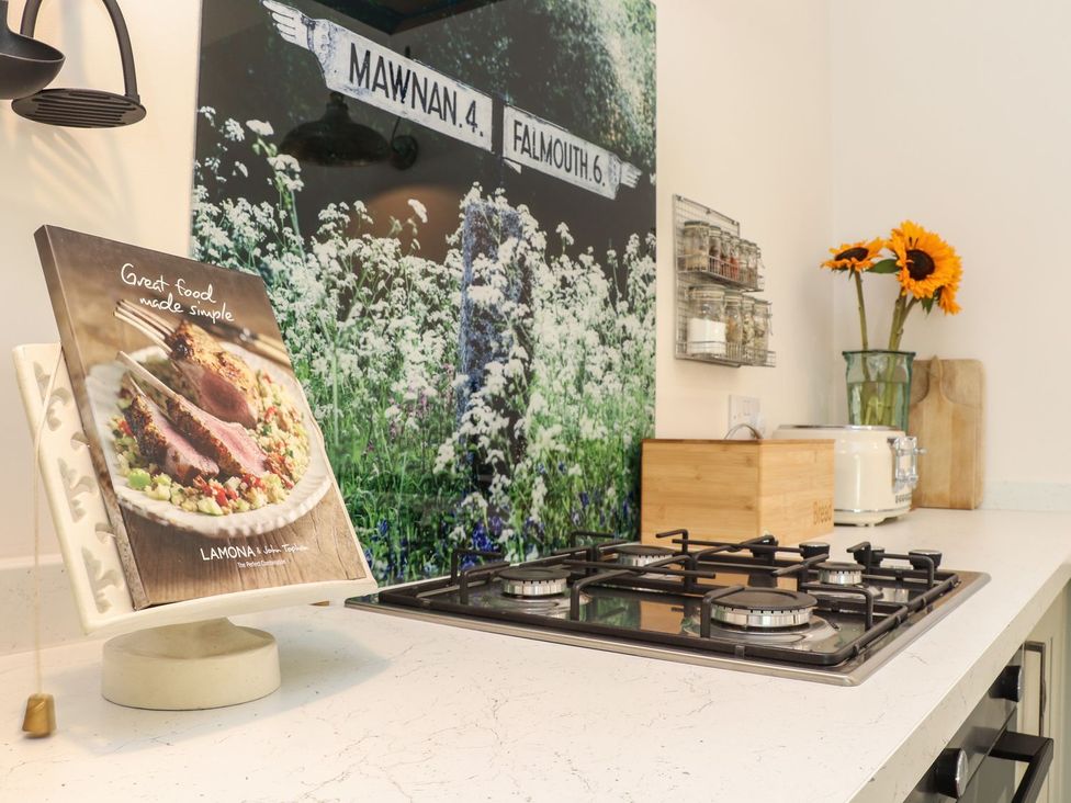 A kitchen with a gas stove and cooking book at The Forge in Falmouth