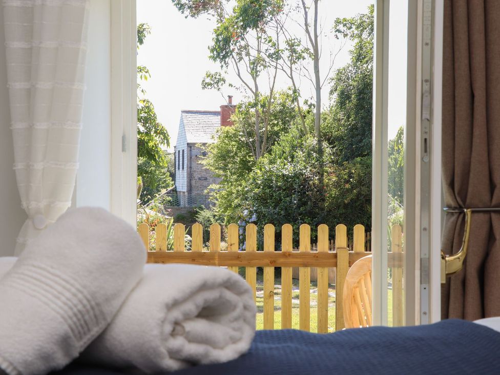 A bedroom view with towels and a window facing a garden at The Forge in Falmouth