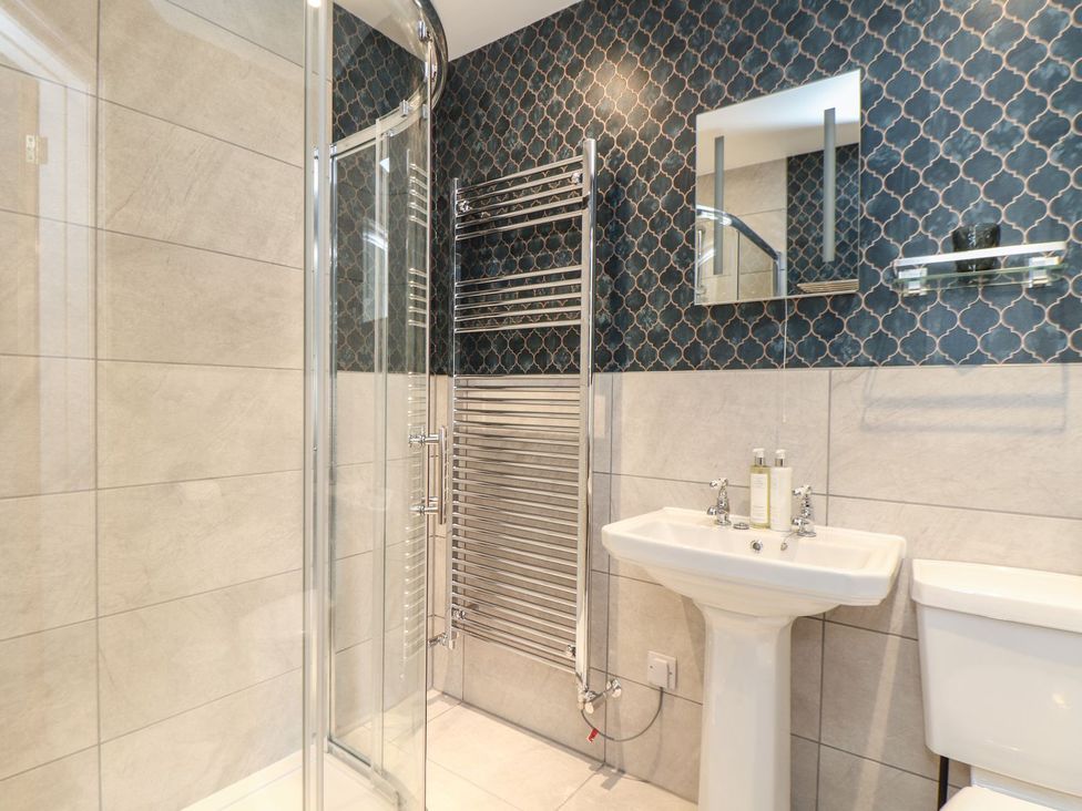 A bathroom with a shower, sink, and heated towel rail at The Forge in Falmouth