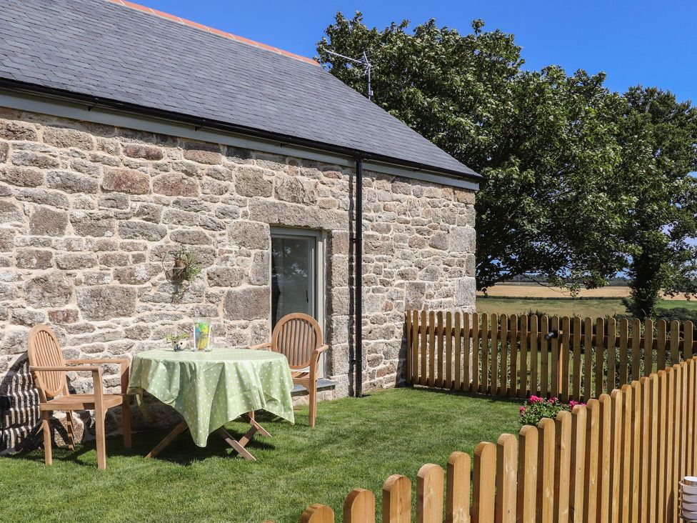 An outdoor area with a table and chairs by a stone wall at The Forge in Falmouth