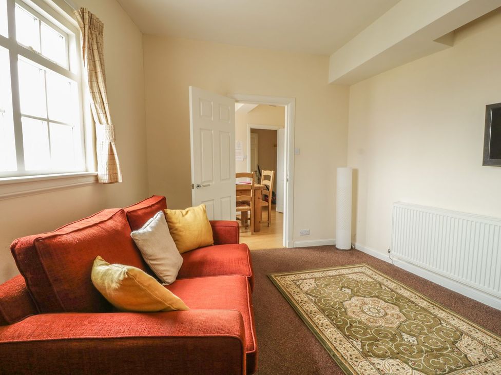 A living room with a sofa and dining area at Cottage No 9 in Keswick