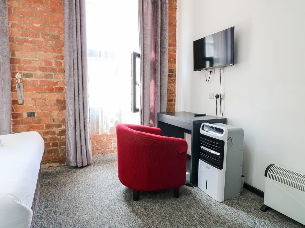 A bedroom with a bed, armchair, television, and table at Apartments 212 in Nottingham