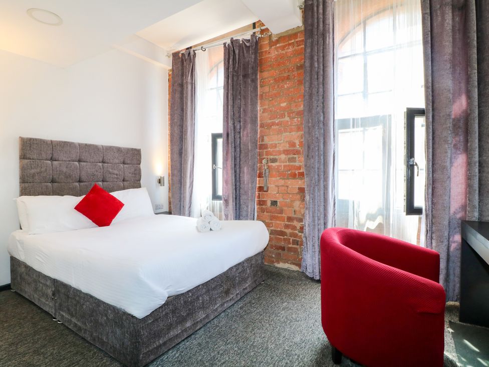 A bedroom with a bed and a red chair at Apartments 212 Nottingham
