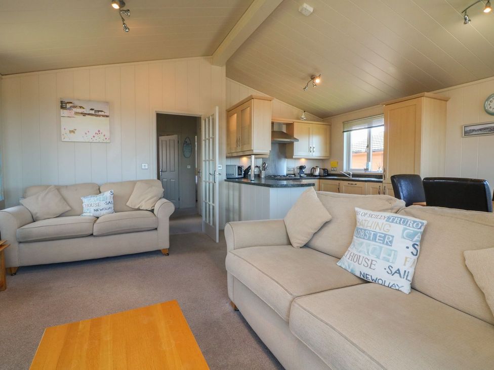 A living room with beige sofas and kitchen area at 1 Ocean Terrace Ilfracombe