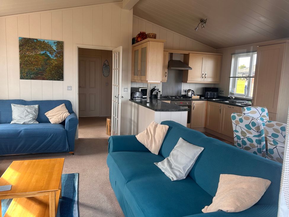 A living room with couches and kitchen area at 1 Ocean Terrace Mullacott near Ilfracombe