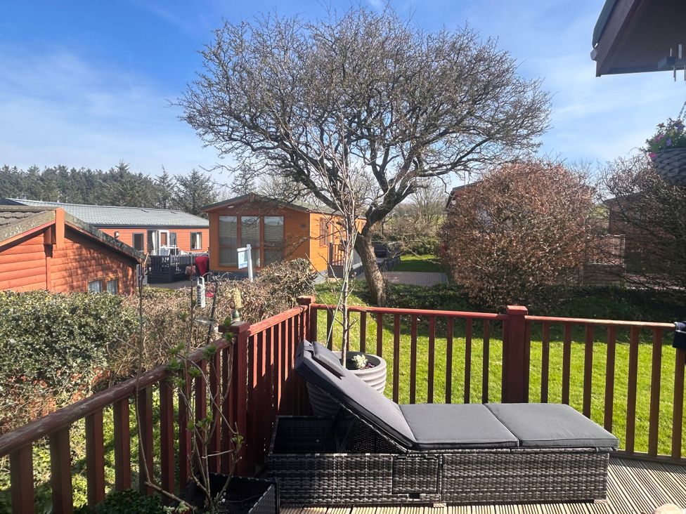 An outdoor patio with a lounge chair and trees at 1 Ocean Terrace Mullacott near Ilfracombe