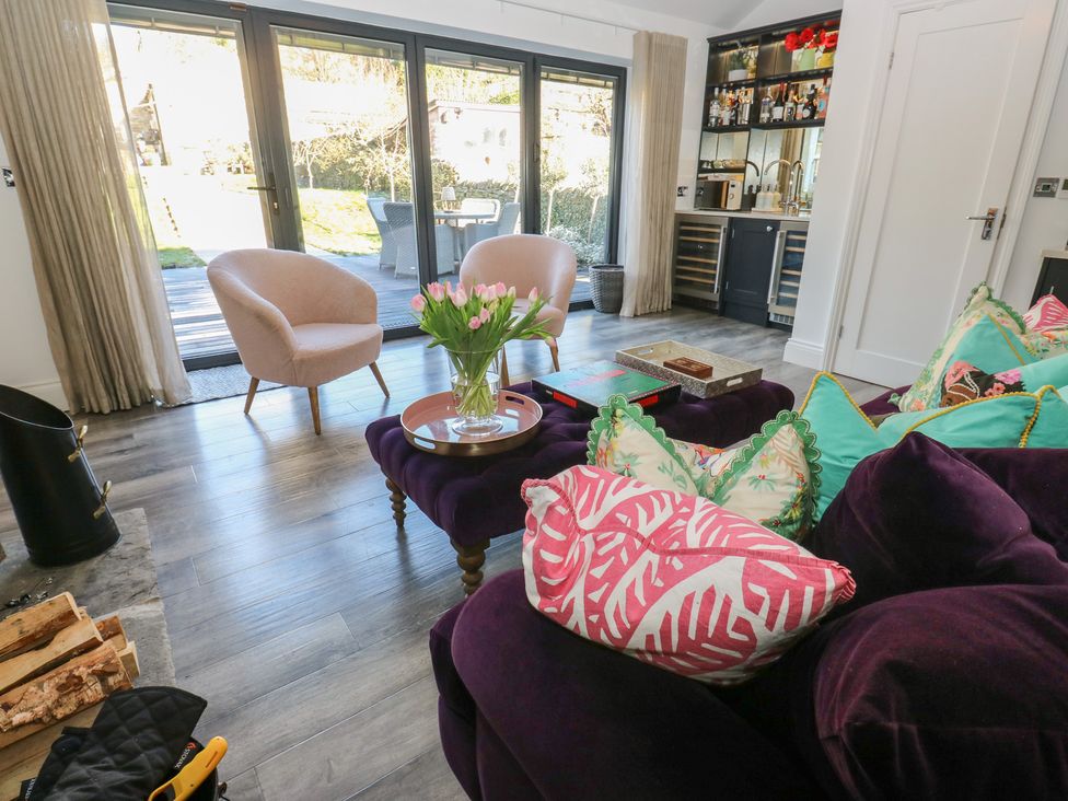 A living room with an armchair, sofa, coffee table, and flowers at The Summerhouse in 