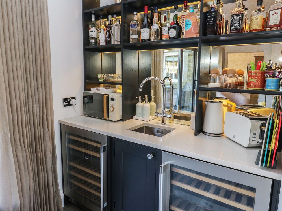 A kitchen area with a sink, bottles, and various appliances at The Summerhouse