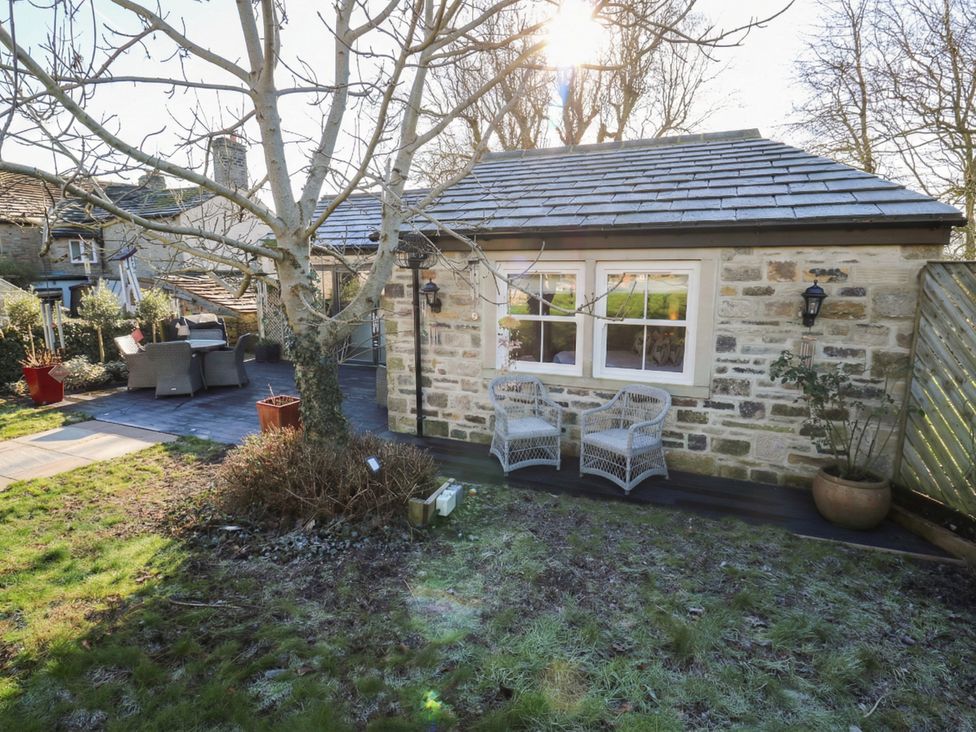 A garden with chairs and a stone building at The Summerhouse in 