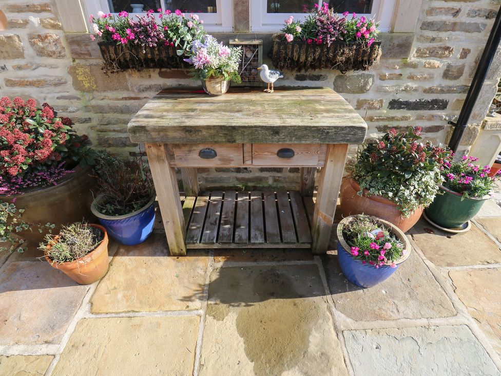 A wooden table with potted plants and flowers in planters at The Summerhouse