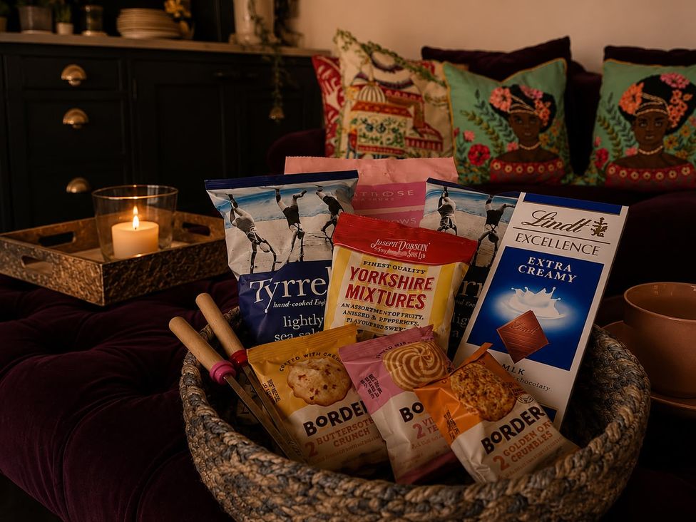A living room with snacks in a basket and a candle at The Summerhouse in Kildwick