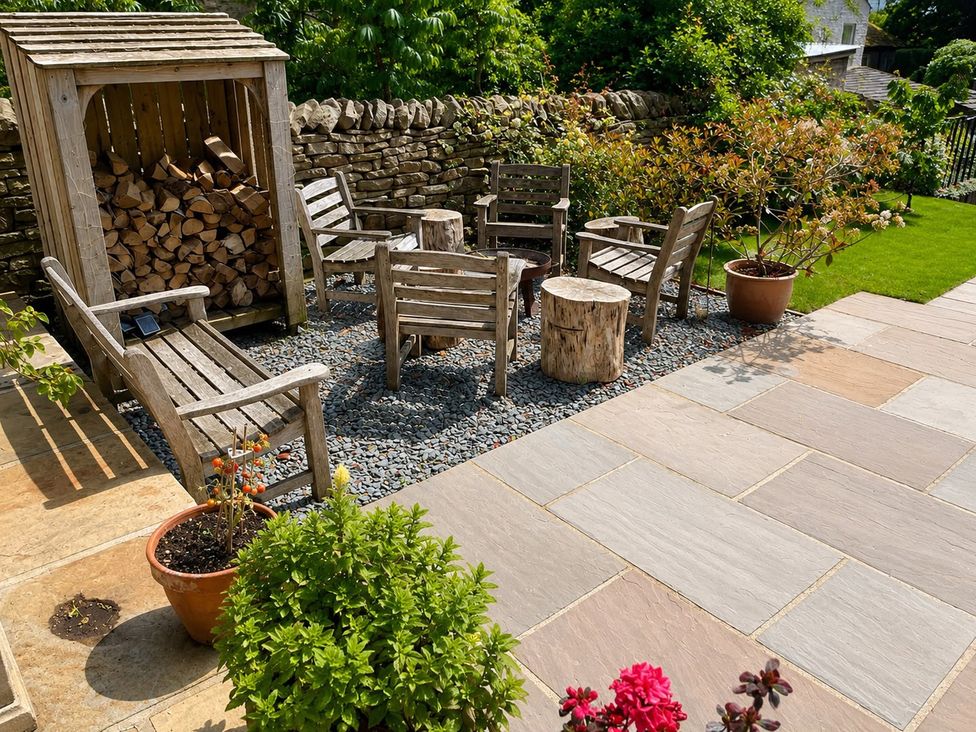 A seating area with wooden chairs and firewood storage at The Summerhouse in Kildwick