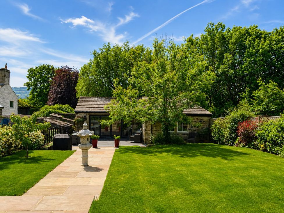 A garden with a pathway and trees at The Summerhouse in Kildwick