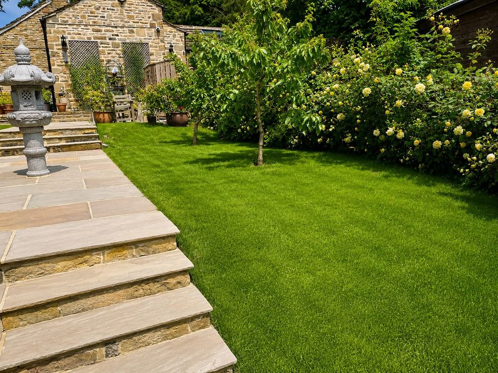 A garden with steps leading to grass and flowers at The Summerhouse in Kildwick